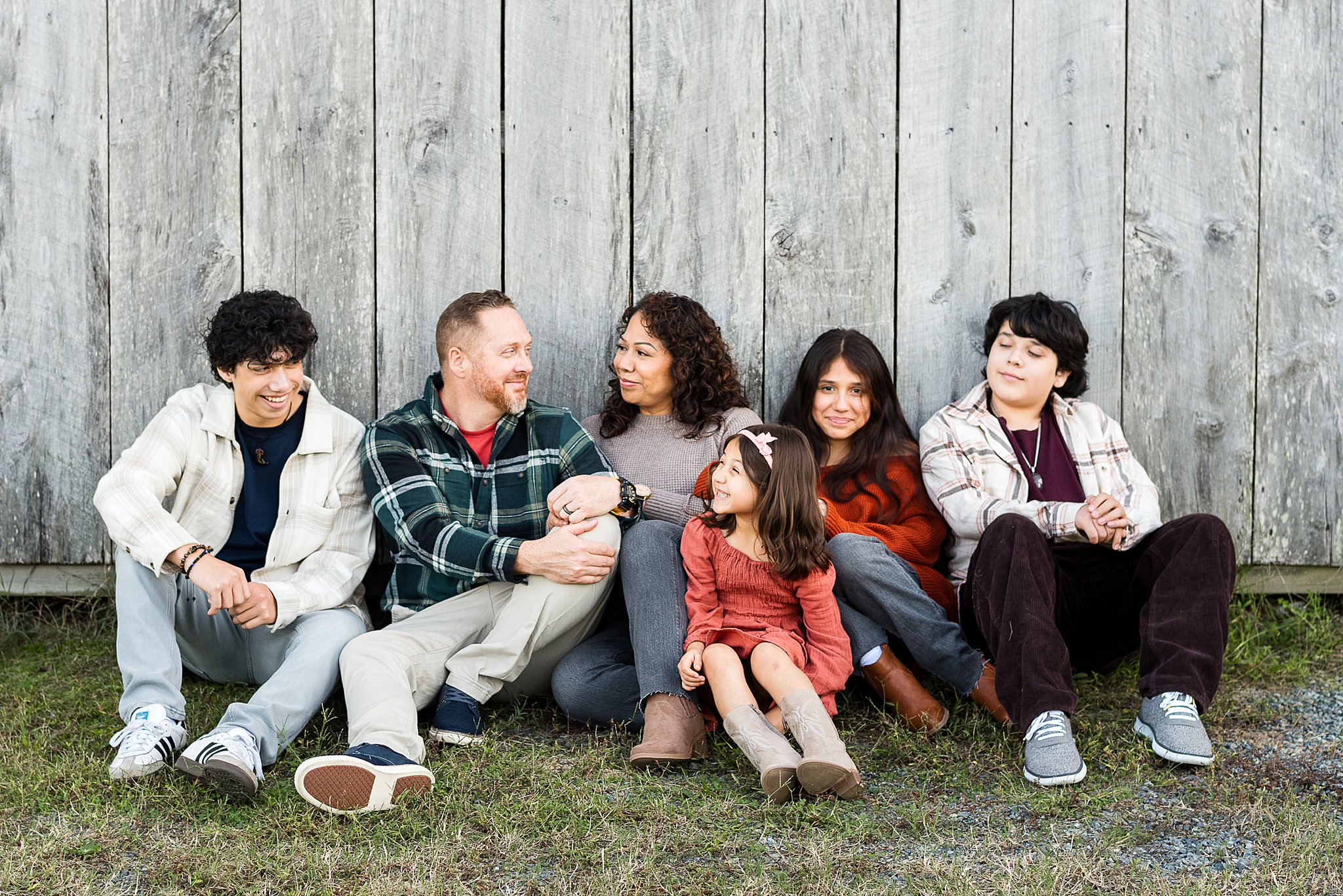 Family of 6 sitting in front of barn